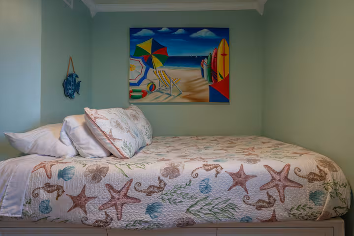 Guest bedroom with queen bed, coastal quilt and beach artwork