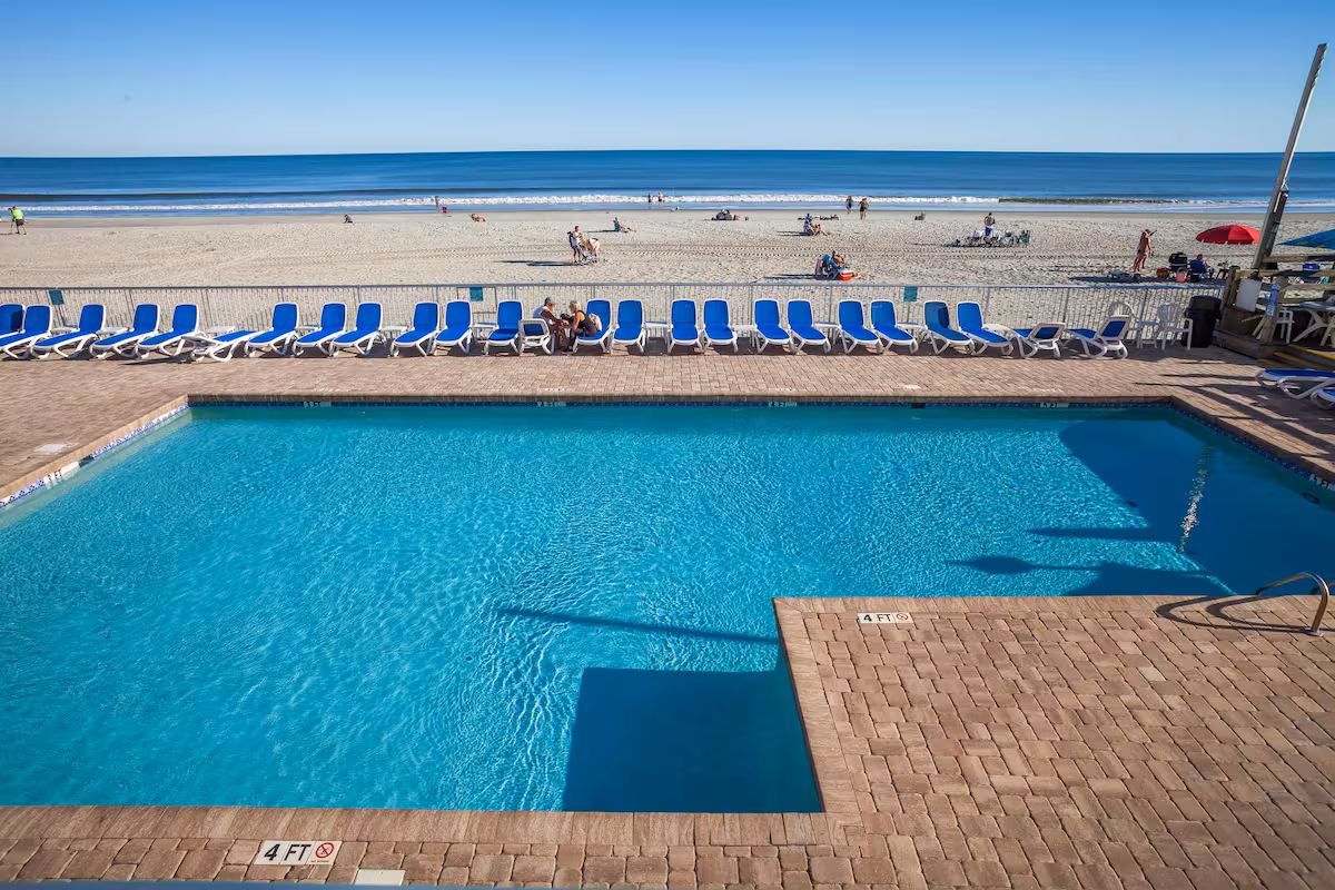 Oceanfront outdoor pool with rows of lounge chairs looking straight out to the beach on Shore Drive in Myrtle Beach