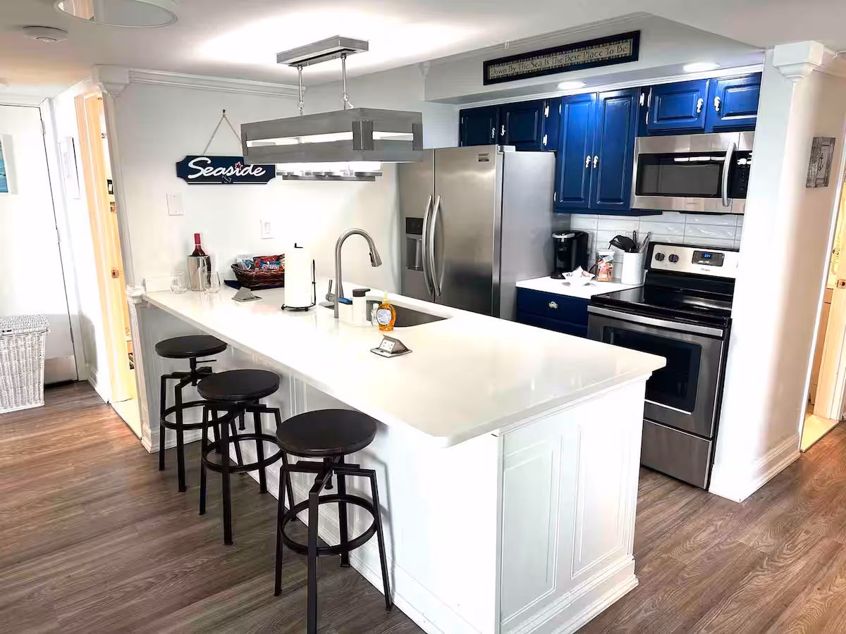 Kitchen with navy cabinets, stainless steel appliances, Keurig coffee bar and a long breakfast bar